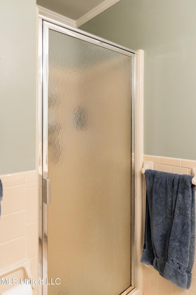 bathroom with a shower with shower door and crown molding