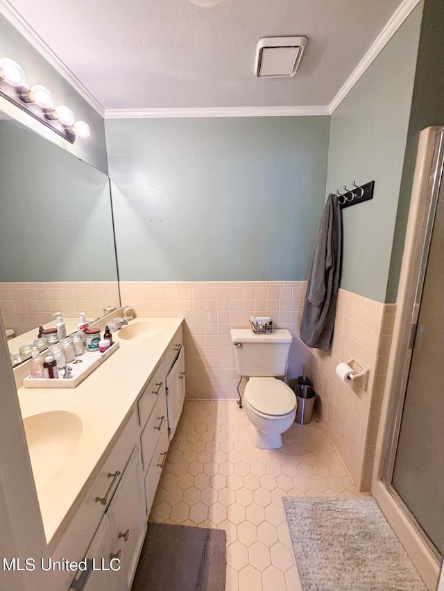 bathroom featuring vanity, tile patterned floors, crown molding, toilet, and tile walls