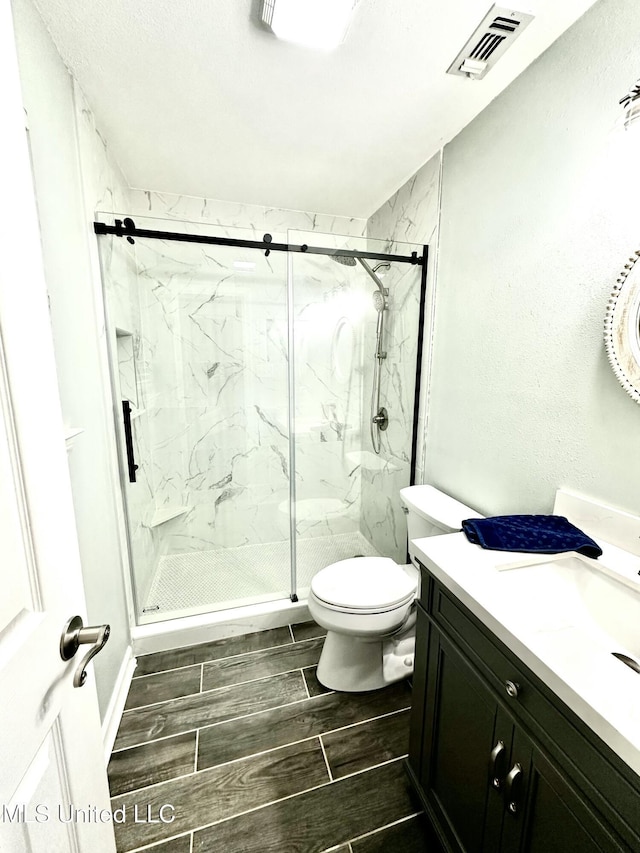 909 Orange St, Ocean Springs, MS 39564 - bathroom with vanity, a marble finish shower, toilet, and wood tiled floors