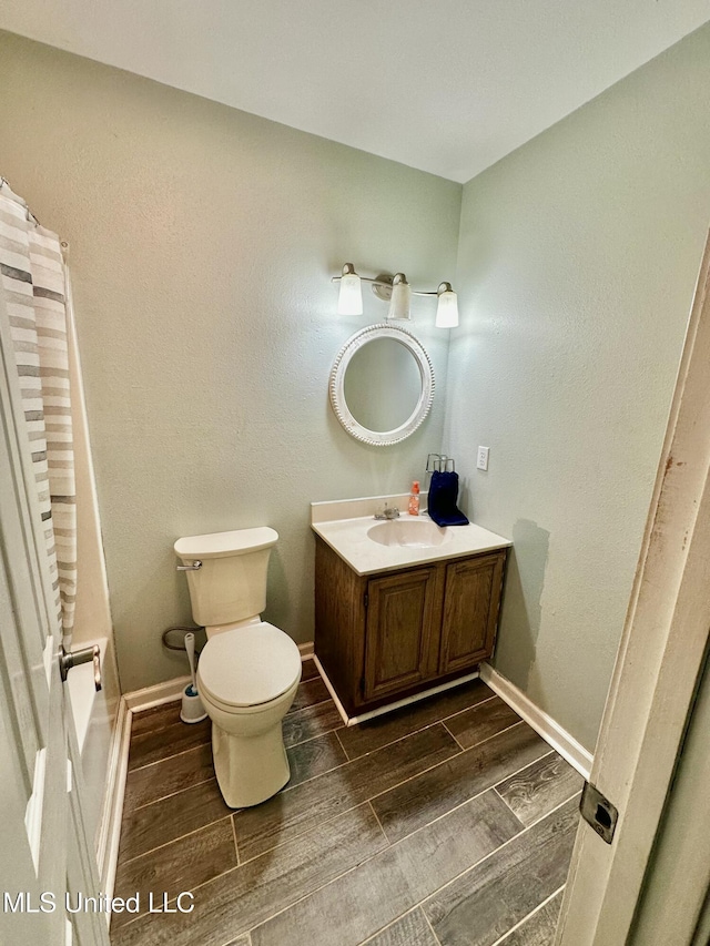 909 Orange St, Ocean Springs, MS 39564 - bathroom with wood tiled floors, toilet, vanity, and baseboards
