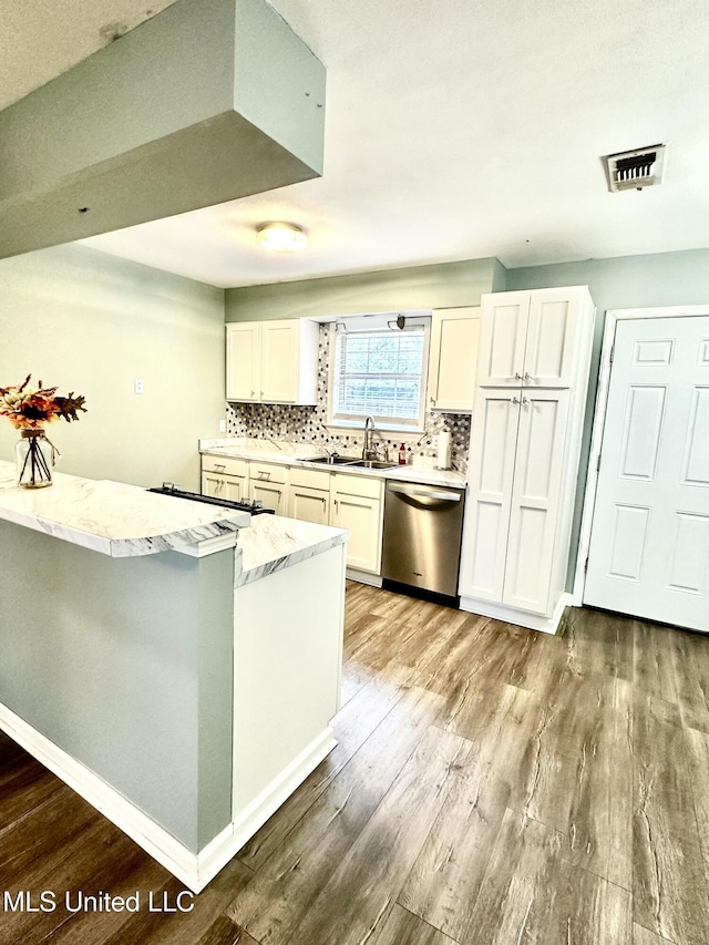 909 Orange St, Ocean Springs, MS 39564 - kitchen featuring stainless steel dishwasher, a sink, wood finished floors, white cabinetry, and decorative backsplash