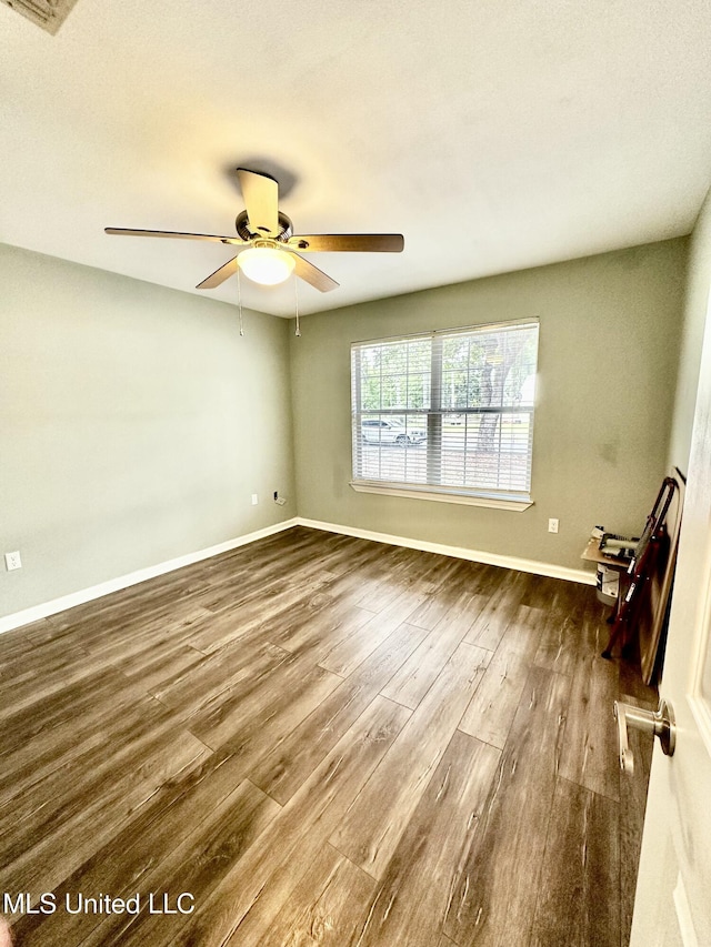 909 Orange St, Ocean Springs, MS 39564 - spare room featuring dark wood finished floors, a ceiling fan, and baseboards