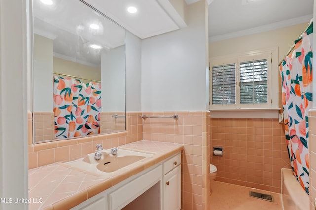 2123 Southwood Rd, Jackson, MS 39211 - full bath featuring vanity, toilet, ornamental molding, tile walls, and a wainscoted wall