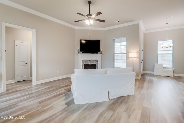 unfurnished living room with ceiling fan with notable chandelier, crown molding, and light hardwood / wood-style flooring