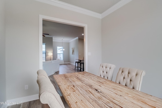 dining space featuring an inviting chandelier, ornamental molding, and hardwood / wood-style flooring