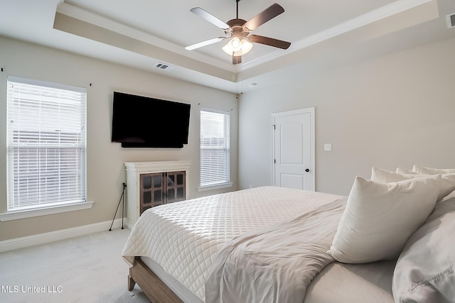 bedroom with a raised ceiling, ceiling fan, light carpet, and ornamental molding