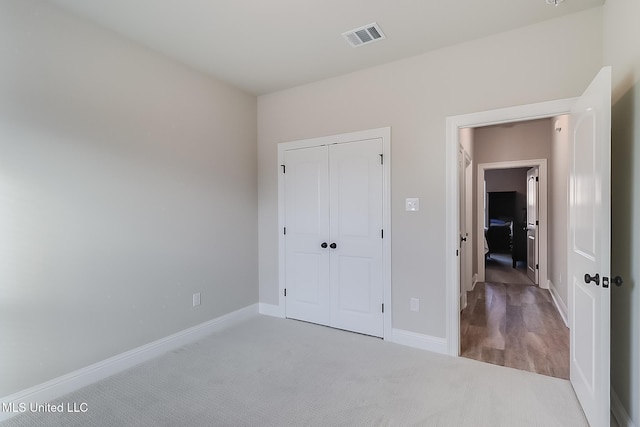 unfurnished bedroom featuring light carpet and a closet