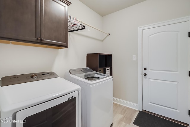 laundry room with cabinets, washer and dryer, and light hardwood / wood-style floors