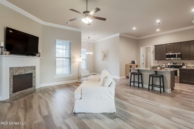 living room featuring ceiling fan with notable chandelier, light hardwood / wood-style floors, and crown molding