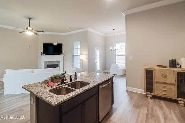 kitchen with stainless steel dishwasher, ceiling fan with notable chandelier, sink, pendant lighting, and a center island with sink