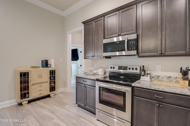 kitchen featuring light hardwood / wood-style flooring, ornamental molding, appliances with stainless steel finishes, dark brown cabinets, and light stone counters