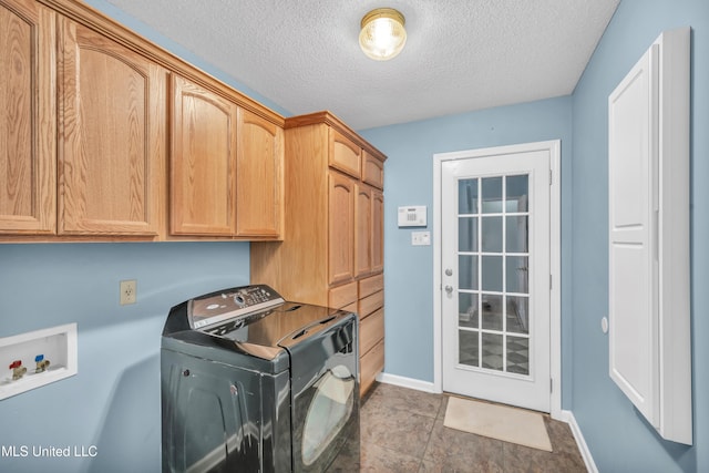 laundry area featuring a textured ceiling, cabinet space, washer / dryer, and baseboards