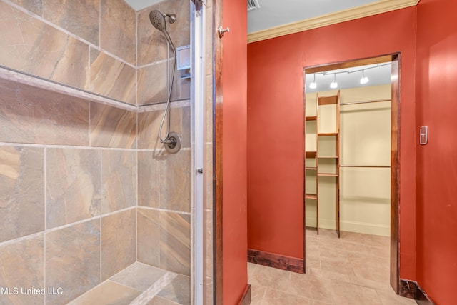 bathroom with baseboards, ornamental molding, a walk in closet, and a shower stall