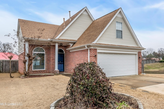 traditional-style home with driveway, roof with shingles, fence, and brick siding