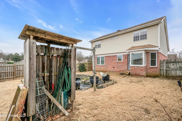 rear view of house featuring entry steps, a fenced backyard, and brick siding