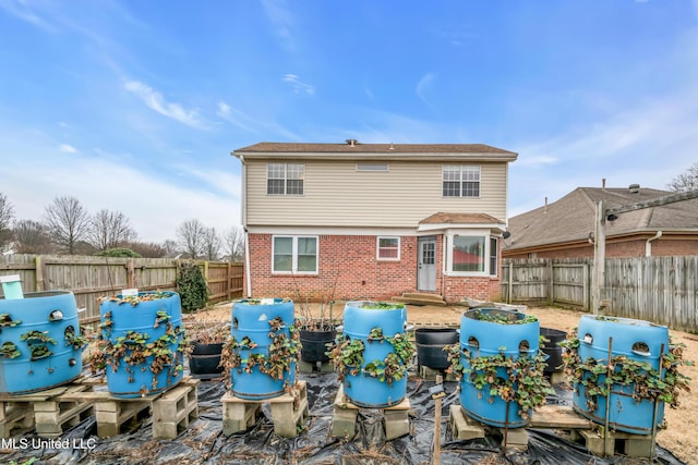 rear view of house featuring entry steps, brick siding, and a fenced backyard