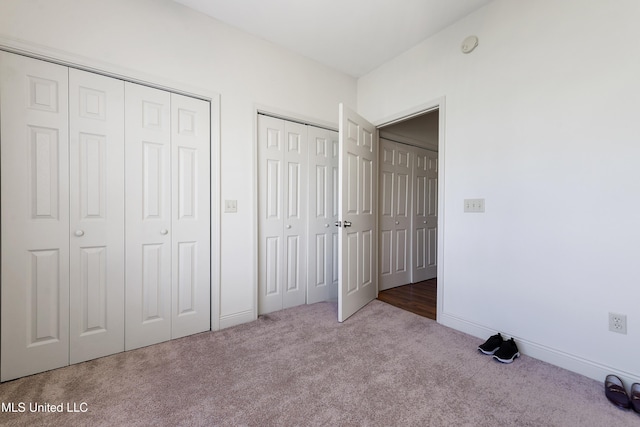 unfurnished bedroom featuring carpet flooring, two closets, and baseboards