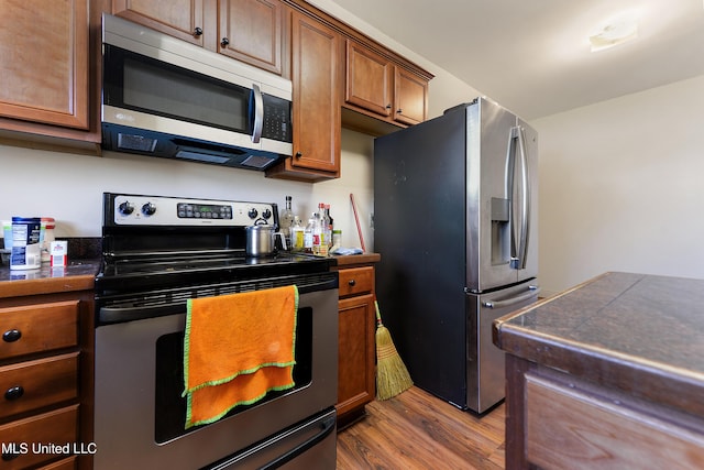 kitchen featuring appliances with stainless steel finishes, brown cabinets, and wood finished floors