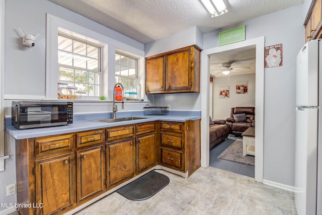 kitchen with sink, ceiling fan, a textured ceiling, and white fridge