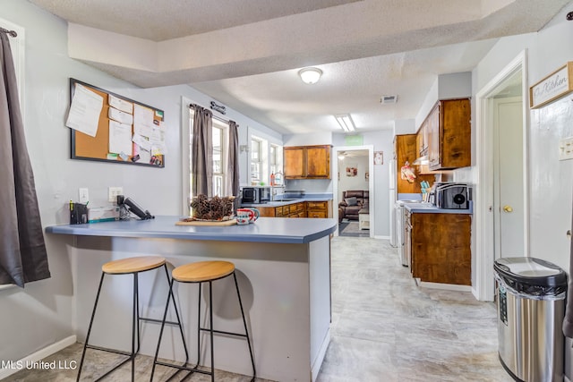 kitchen featuring a kitchen breakfast bar, kitchen peninsula, and a textured ceiling