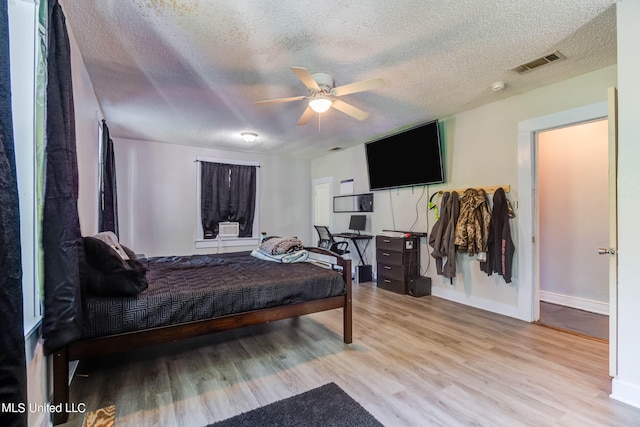 bedroom featuring a textured ceiling, light hardwood / wood-style floors, and ceiling fan