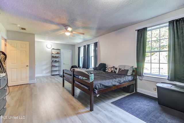 bedroom featuring ceiling fan, multiple windows, and light hardwood / wood-style flooring