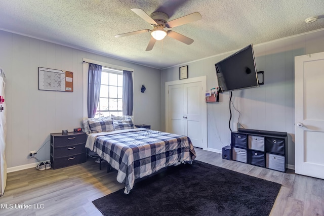 bedroom featuring ceiling fan, light hardwood / wood-style floors, and a textured ceiling