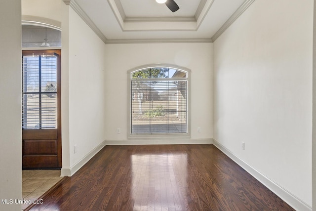 empty room with crown molding, dark hardwood / wood-style flooring, a raised ceiling, and a wealth of natural light