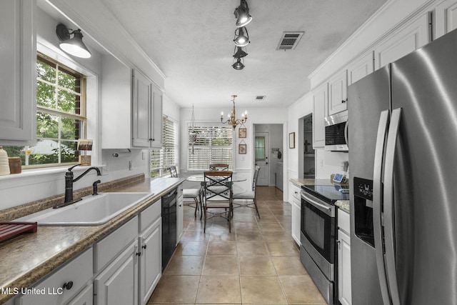 215 Cobblestone Dr, Madison, MS 39110 - kitchen with appliances with stainless steel finishes, a chandelier, white cabinets, and light tile patterned floors