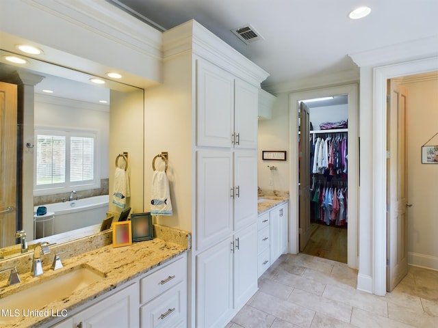 bathroom with tile patterned flooring, vanity, a tub to relax in, and ornamental molding