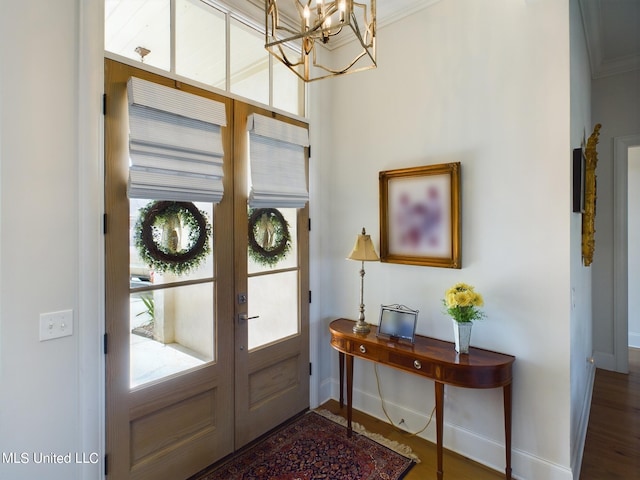 entryway with french doors, dark hardwood / wood-style flooring, ornamental molding, and a notable chandelier