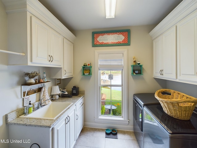 laundry room featuring sink, light tile patterned floors, cabinets, and independent washer and dryer