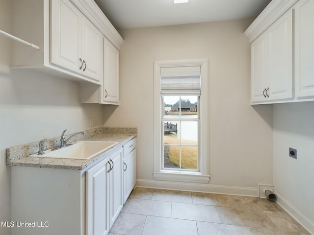 laundry area featuring cabinets, light tile patterned floors, electric dryer hookup, and sink