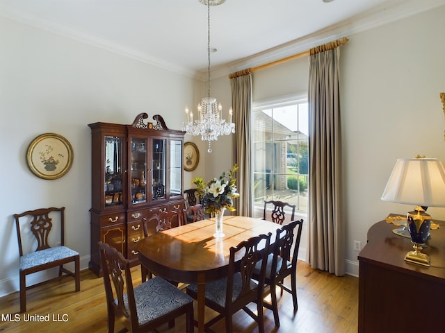 dining space with light wood-type flooring, a notable chandelier, and ornamental molding