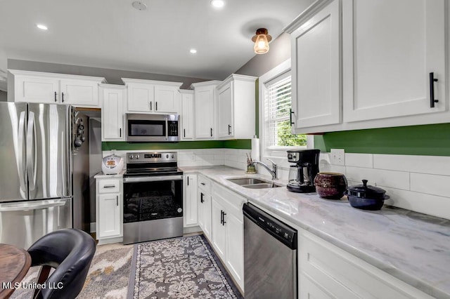2085 Pat Ln, Biloxi, MS 39531 - kitchen featuring stainless steel appliances, a sink, white cabinets, light stone countertops, and backsplash