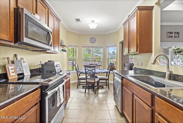 21915 Huntington Forest Dr, Saucier, MS 39574 - kitchen featuring appliances with stainless steel finishes, a sink, crown molding, brown cabinetry, and baseboards