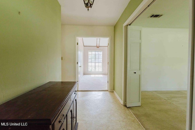 hall featuring baseboards, visible vents, and attic access
