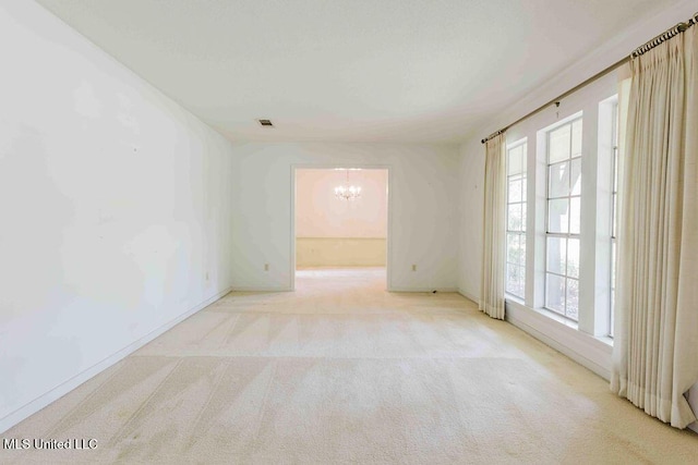 carpeted spare room with baseboards and a notable chandelier