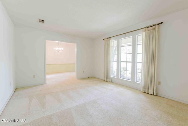 carpeted empty room featuring baseboards, a chandelier, and visible vents