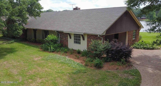 exterior space with a lawn, a chimney, and a shingled roof
