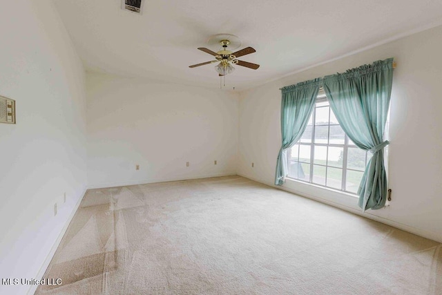 spare room featuring visible vents, a ceiling fan, and light colored carpet