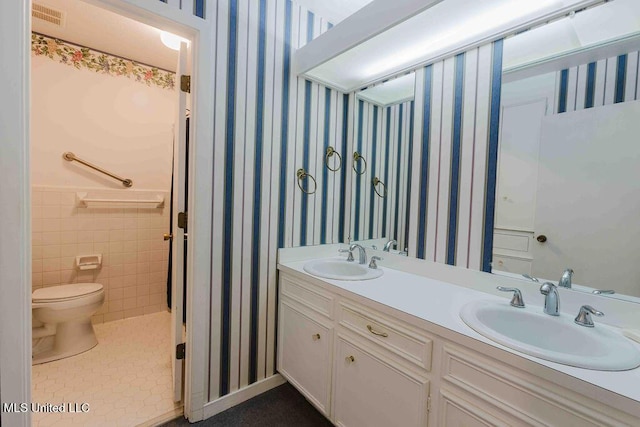 full bath featuring a sink, toilet, wallpapered walls, and double vanity