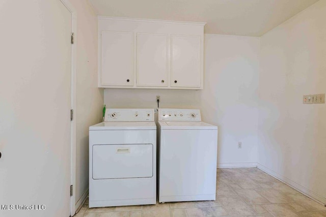washroom with baseboards, cabinet space, and washer and dryer