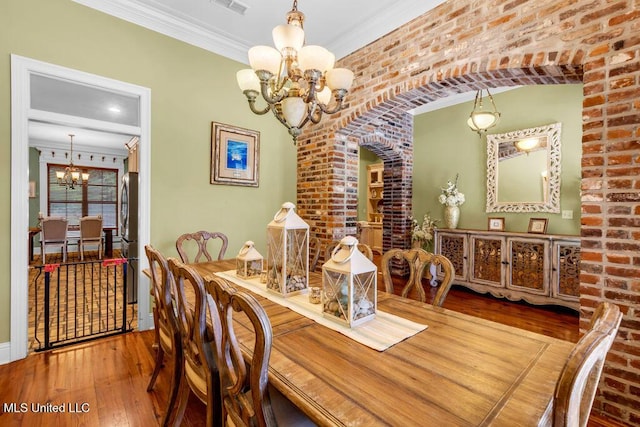 769 Mclane Ln, Biloxi, MS 39532 - dining space featuring a chandelier, hardwood / wood-style flooring, ornamental molding, and brick wall