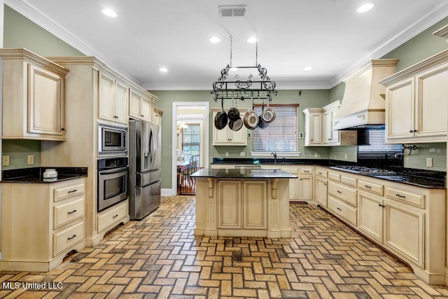 769 Mclane Ln, Biloxi, MS 39532 - kitchen with stainless steel appliances, custom range hood, brick flooring, cream cabinetry, and crown molding