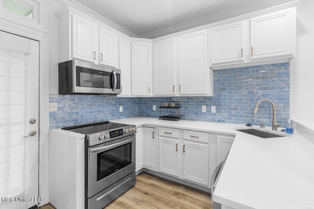 kitchen featuring tasteful backsplash, white cabinetry, light wood-type flooring, sink, and stainless steel appliances