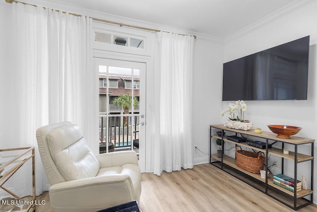 sitting room with crown molding and light wood-type flooring