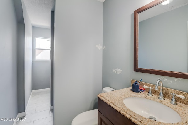 bathroom with vanity, baseboards, tile patterned floors, and toilet