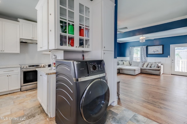 washroom featuring a wainscoted wall, laundry area, washer / clothes dryer, and a wealth of natural light