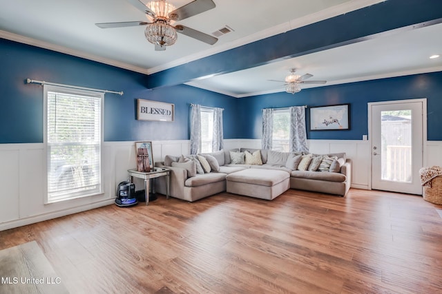 living room featuring a wainscoted wall, a ceiling fan, wood finished floors, visible vents, and ornamental molding